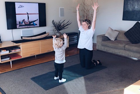 Woman and child stretching watching Yoga on The Studio HQ Online